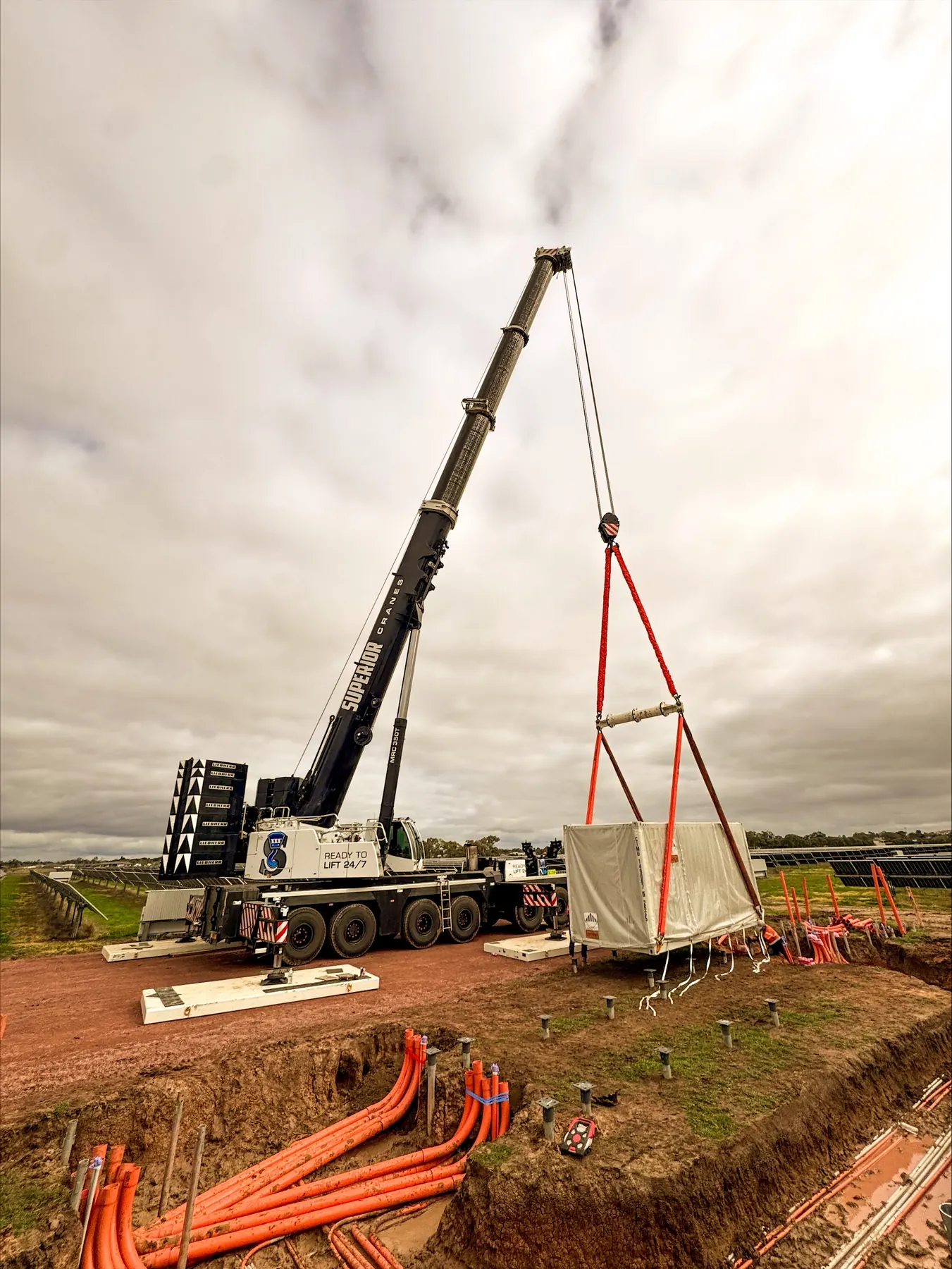 A crane lifting a cage over a trench