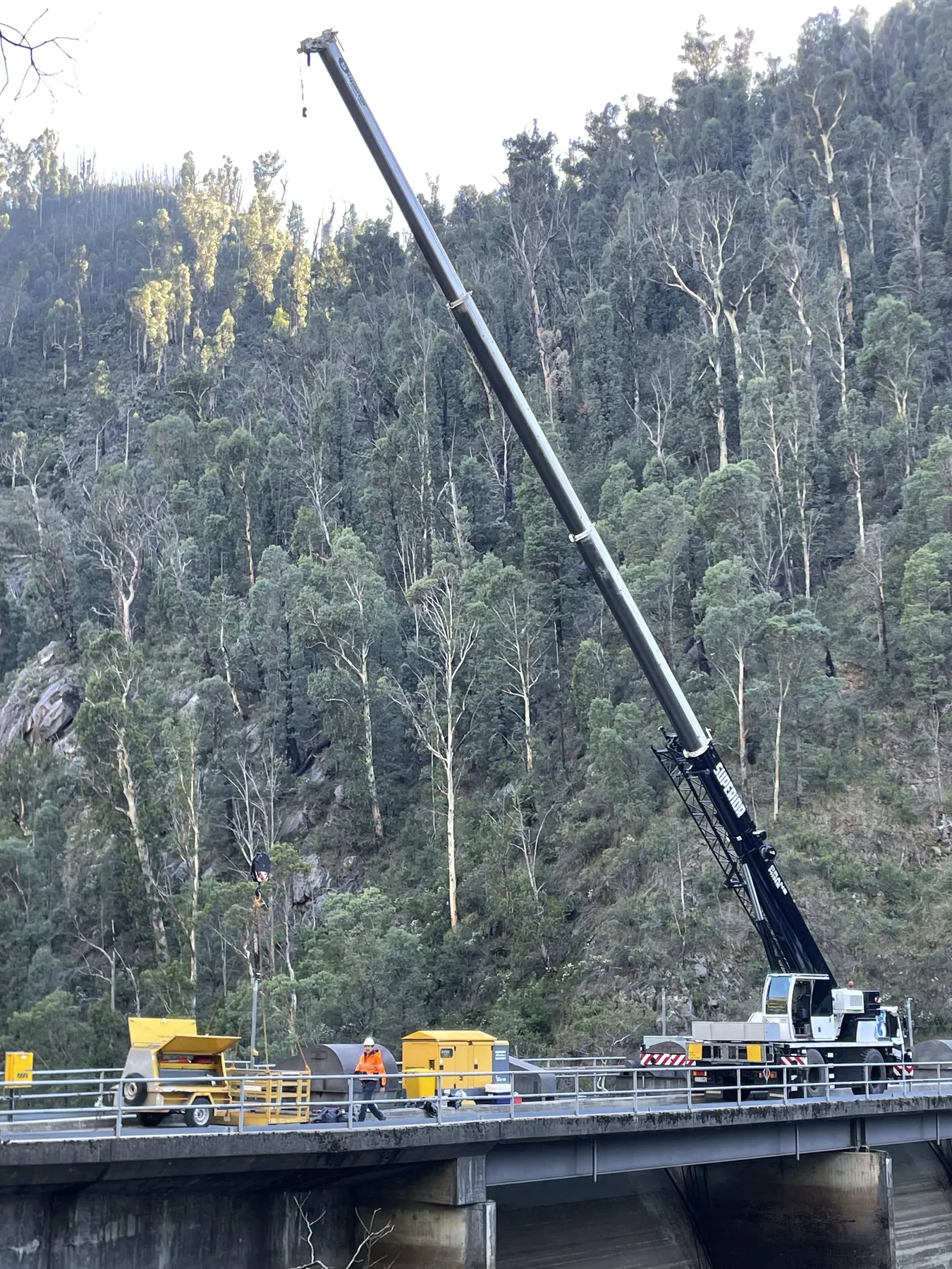 Crane working on a bridge in steep forest country