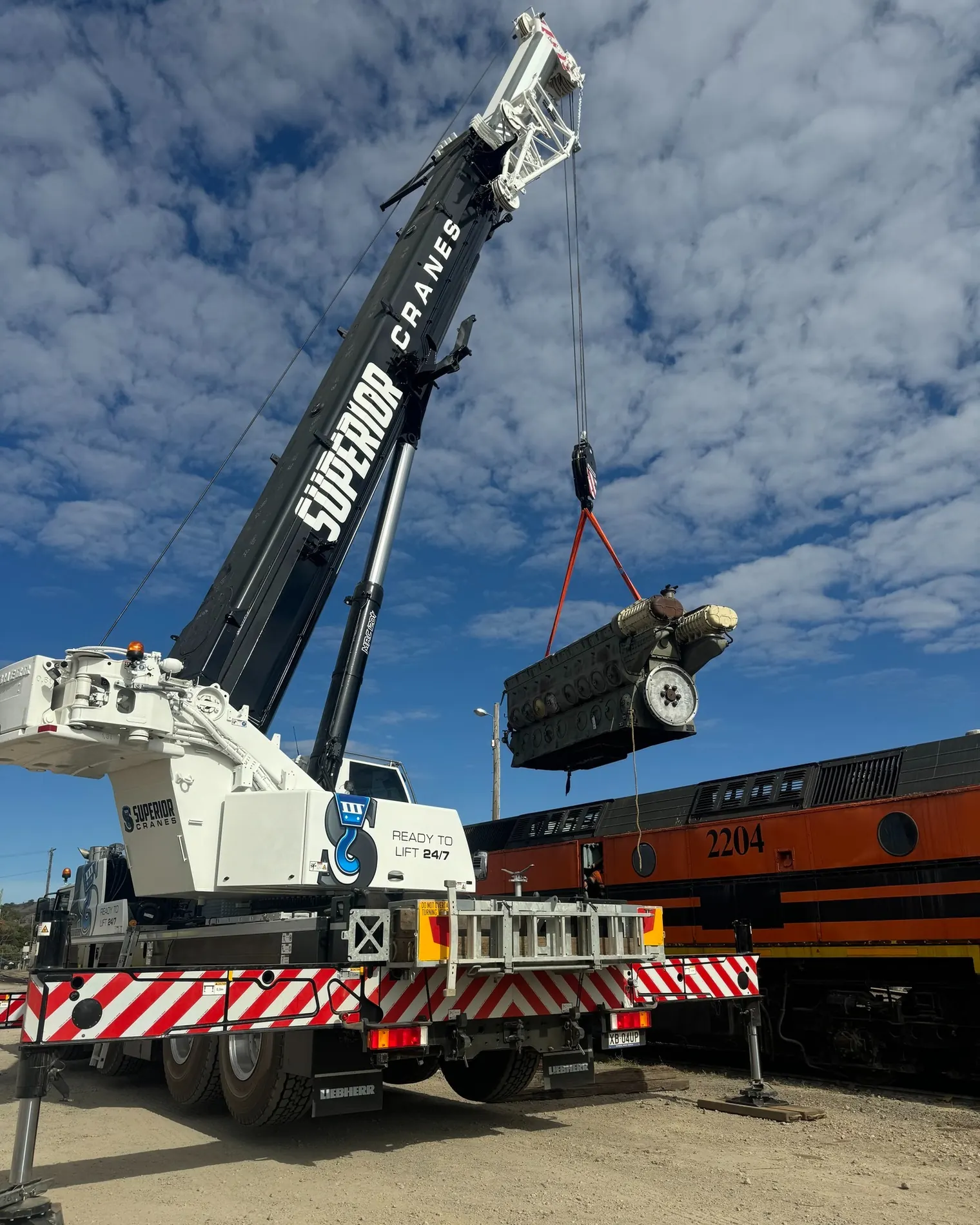 Crane lifting machinery beside a train
