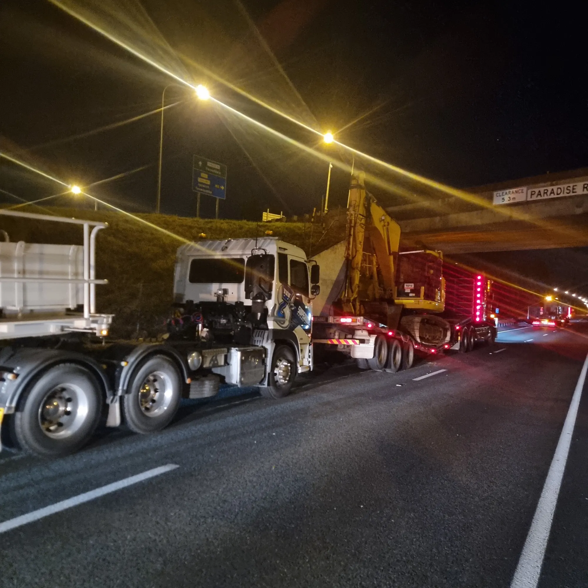 Excavator being loaded onto a float at night