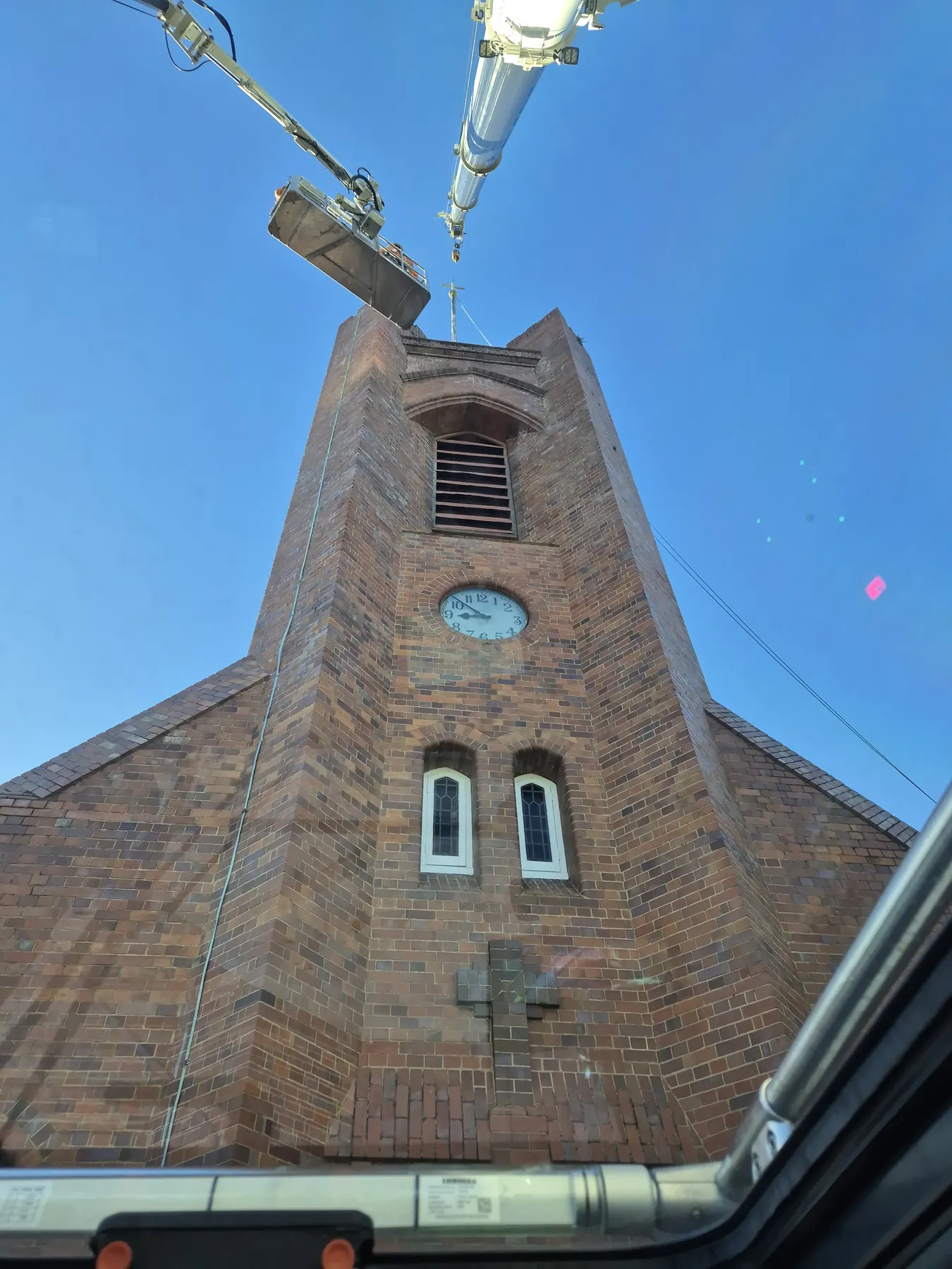 Crane lifting a spire onto a heritage brick church